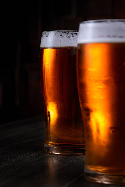 a glass of foamy beer on a dark background - Photo, image