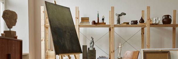 Unique artist workspace interior with stylish teak commode, wooden easel, bookcase, artworks, painting accessories, decoration and elegant personal stuff. Modern work room for artist. Template. - Φωτογραφία, εικόνα