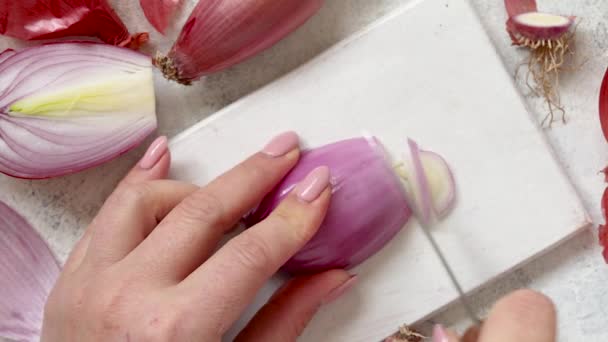 Mãos de mulher cortando tropea fresca cebola vermelha em uma tábua de madeira de perto, conceito de cozinhar em casa na cozinha - Filmagem, Vídeo