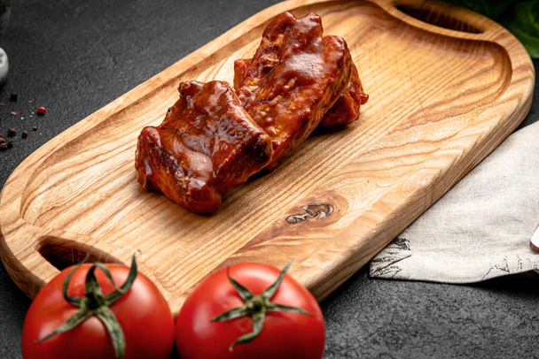 fried ribs in sauce served on a board, on a dark background - Photo, Image
