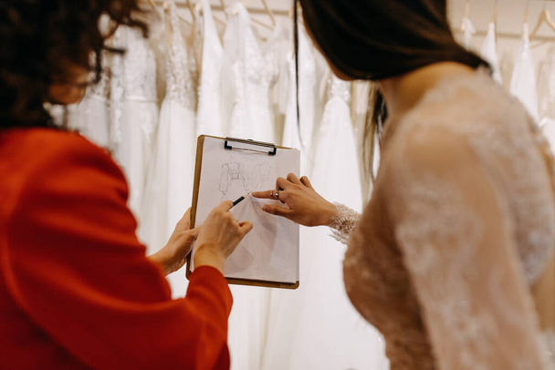 Дизайнер моди, що показує ескізи весільної сукні клієнту в шоу-румі
. - Фото, зображення
