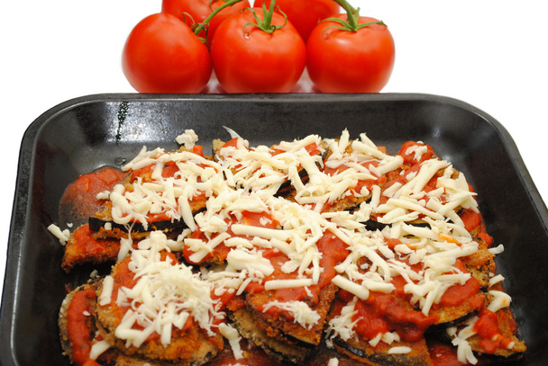 Pan de berenjena parmesano con tomates en el fondo
 - Foto, imagen