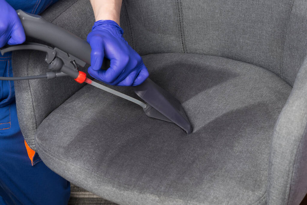 specialist, collects water with cleaning agent from the drapery of the chair with a cleaning vacuum cleaner - Foto, imagen