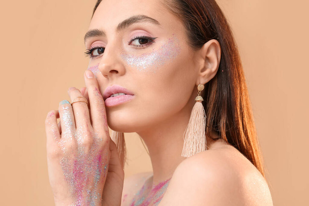 Beautiful young woman with glitters on her face and body against color background - Foto, immagini