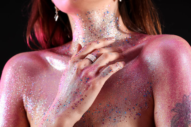 Beautiful young woman with glitters on her body against dark background, closeup - 写真・画像