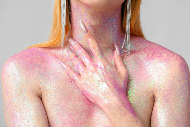 Fashionable young transgender woman with glitters on body against light background, closeup - Photo, Image