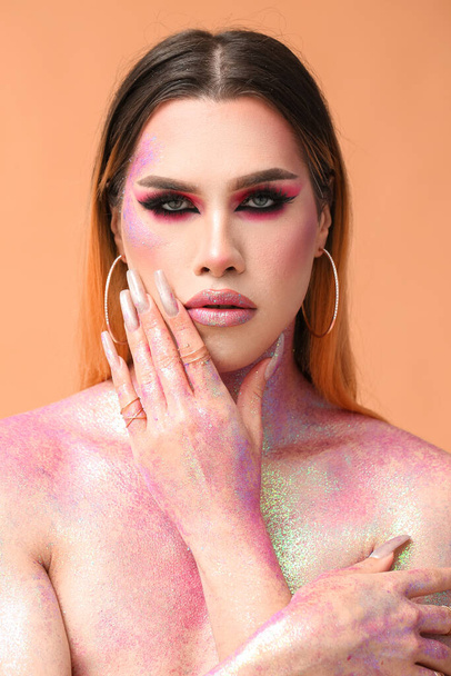Fashionable young transgender woman with glitters on body against color background - Photo, Image