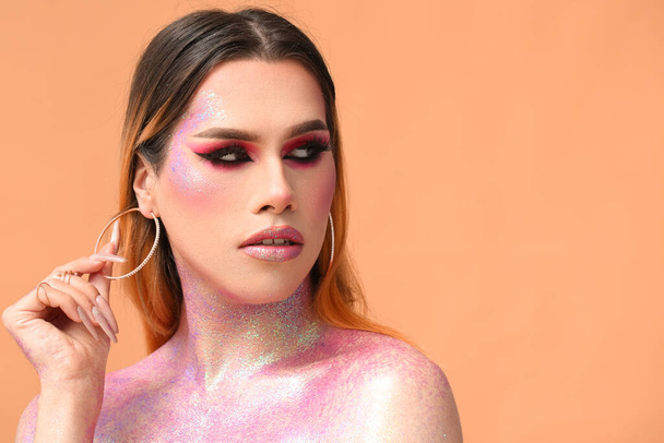 Fashionable young transgender woman with glitters on body against color background - Foto, imagen