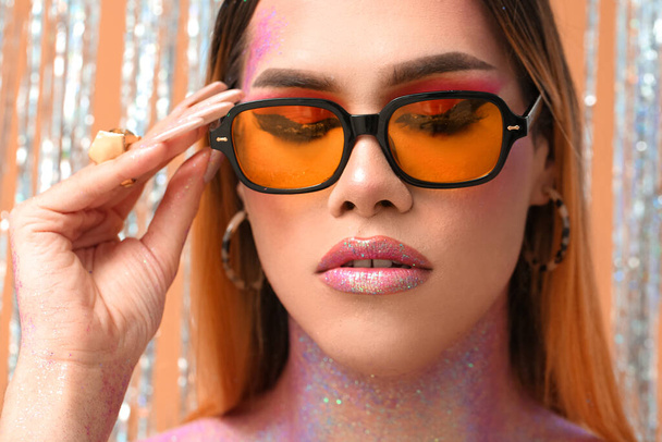 Fashionable young transgender woman with glitters on body against color background - Foto, imagen
