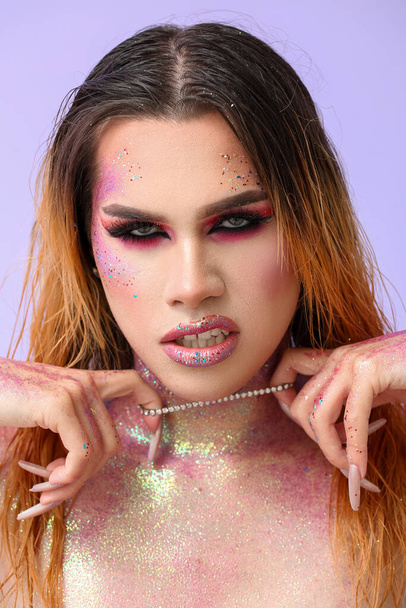Μοντέρνα νεαρή τρανσέξουαλ γυναίκα με γκλίτερ στο σώμα με φόντο το χρώμα - Φωτογραφία, εικόνα