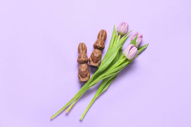 Chocolate Easter bunnies and beautiful tulip flowers on lilac background - Foto, afbeelding