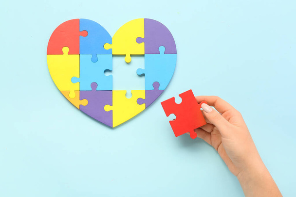 Woman and heart made of puzzle pieces on blue background. Concept of autistic disorder - Photo, Image