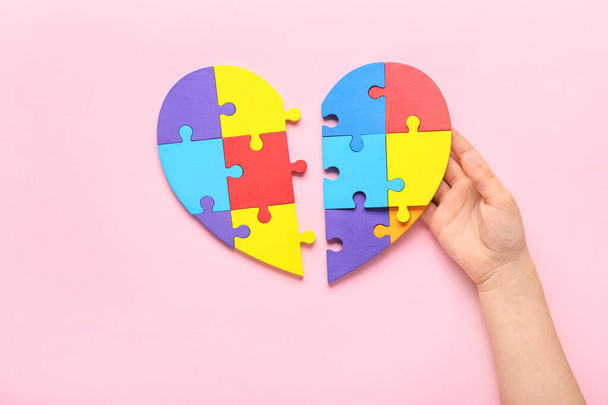 Child with puzzle pieces on pink background. Concept of autistic disorder - Photo, Image