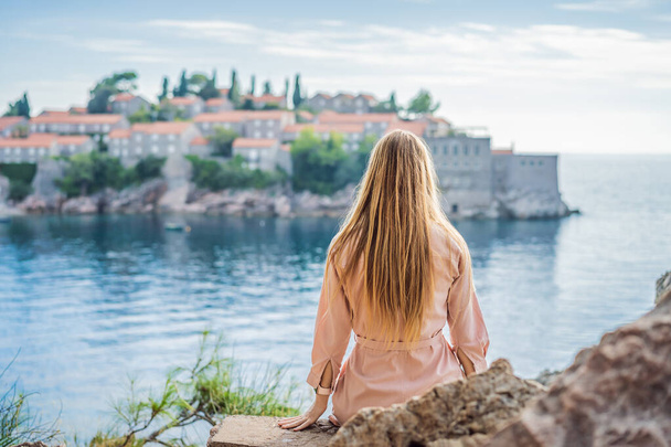 Donna turista sullo sfondo della splendida vista dell'isola di Santo Stefano, Sveti Stefan sulla riviera di Budva, Budva, Montenegro. Viaggio in Montenegro concetto - Foto, immagini