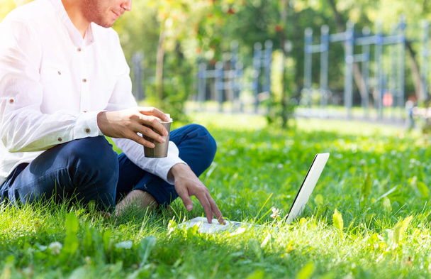 Businessman using laptop computer on green grass - Фото, изображение