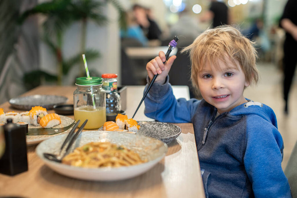 Child, eating japanese sushi and noodles with chopsticks in a restaurant, dinnertime - Valokuva, kuva