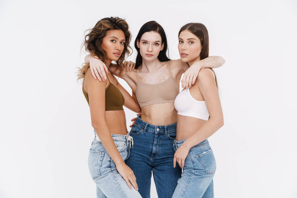 Young three women wearing bra hugging and looking at camera isolated over white background - Фото, зображення