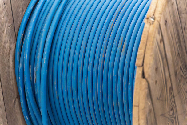 Nuovo cavo di alimentazione blu è avvolto su bobina di legno. Contesto. - Foto, immagini