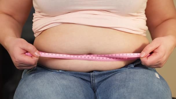 Nuori ylipainoinen tai plus koko nainen, jolla on lihava, iso vatsa, joka mittaa vatsan ympärysmittaa, ihmisten elämää xl koko, paksu ja rasva käsite - Materiaali, video