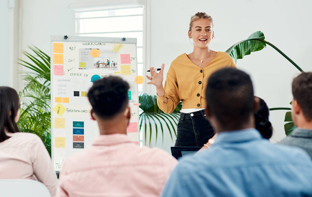 This is our new game plan. Cropped shot of an attractive young businesswoman standing and giving a presentation to her colleagues in the office. - Photo, Image