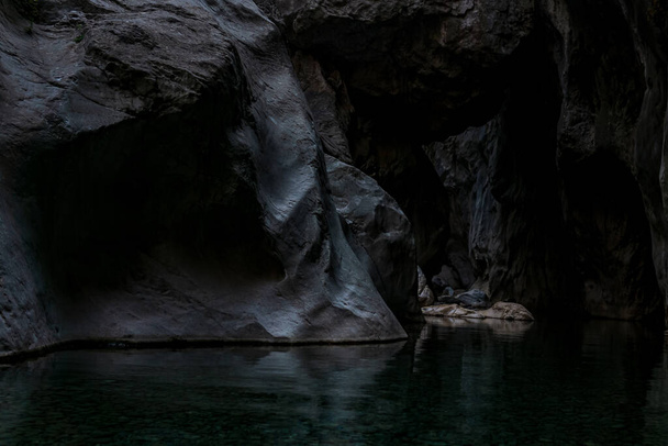 чиста підземна печера в крутих кам'яних берегах в темряві
 - Фото, зображення