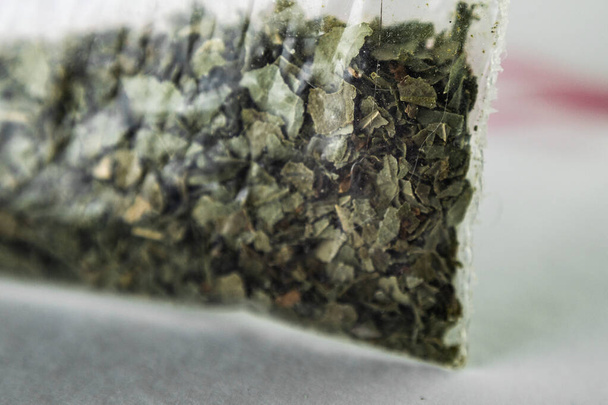 green dry crushed leaves (marijuana, tobacco) in a plastic bag - Photo, Image