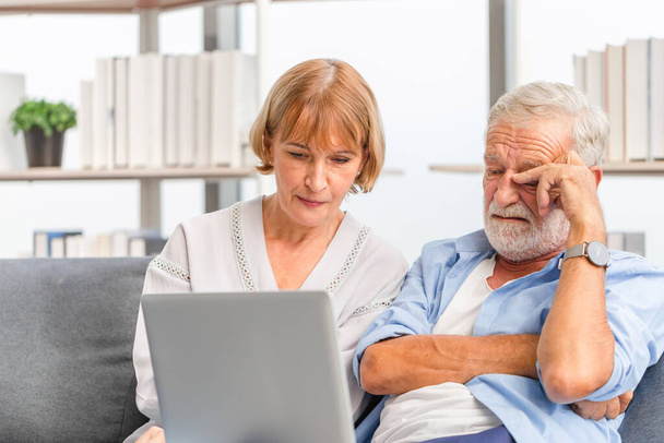 Portret zamartwionej pary seniorów sprawdzających rachunki i pracujących nad netbookiem czytających w domu informacje o dokumentach, Poważna emerytowana starsza rodzina czytająca dokumenty z laptopem - Zdjęcie, obraz