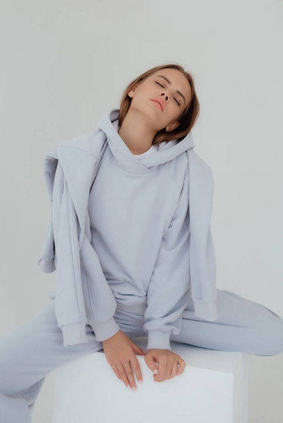 Ukrán fiatal nő pulóverben gúnyolódik a könnyű háttérrel. Női test és stílus koncepció. Reklám vagy ruha eladó design. Mock up a design, ruhaüzlet eladó. - Fotó, kép