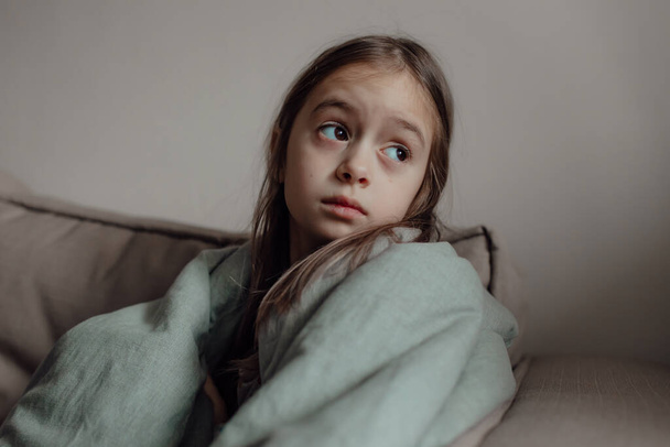 Stop de oorlog. Bid voor Oekraïne. Wij staan aan de kant van Oekraïne. Oekraïense bange kind onder een deken. Het meisje is bang voor de geluiden van luchtaanvallen en explosies. Arm kind met verdriet en verdriet, pech en verdriet.  - Foto, afbeelding