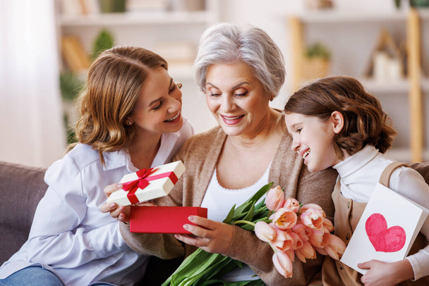 幸せな国際女性の日。祖母に花を贈る娘と孫娘｜母の日を自宅で祝う - 写真・画像