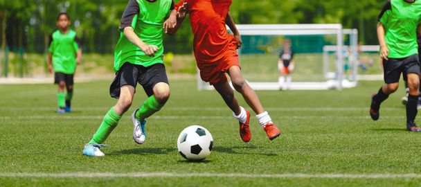 Οριζόντια εικόνα εφήβων που παίζουν ποδόσφαιρο. Ευτυχισμένα αγόρια κλωτσάνε κλασσική μπάλα ποδοσφαίρου στο γρασίδι. Τα παιδιά των σχολείων ανταγωνίζονται σε αθλητικό παιχνίδι σε αγωνιστικό γήπεδο - Φωτογραφία, εικόνα