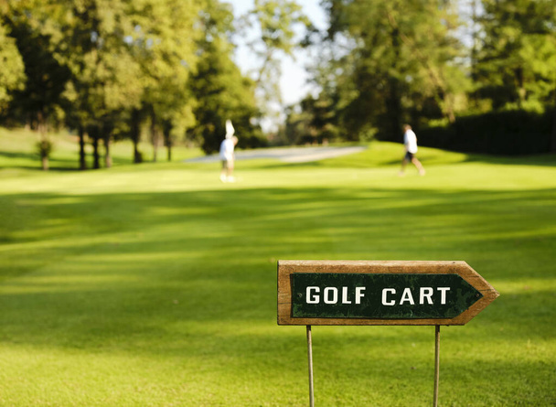 Značka v blízkosti zelené označující zákaz jízdy golfovým autem. V pozadí zelená s hráči. - Fotografie, Obrázek
