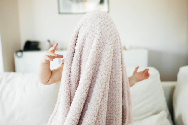 Αξιολάτρευτο κοριτσάκι που κρύβεται πίσω από την κουβέρτα - Φωτογραφία, εικόνα