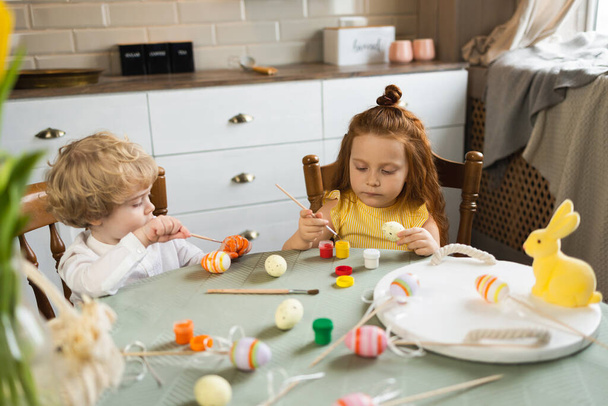 Boy and girl painting Easter eggs with paints and brushes - Photo, Image