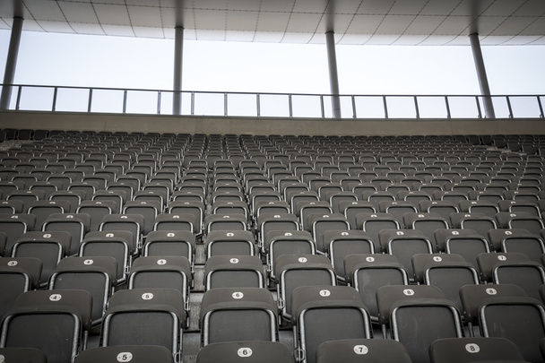 кілька рядів сидінь на стадіоні сірого кольору, стріляти з фронту
 - Фото, зображення