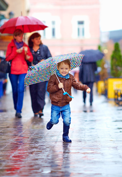 happy boy running through rainy city street - Φωτογραφία, εικόνα