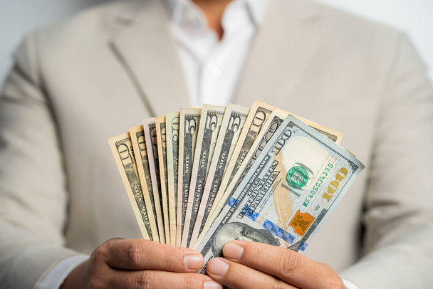 Business man and money in us dollar hold on hand wearing a brown suit jacket and Give to me USD, Pay, exchange money on white background. Business finance and bank employee Concept. - Fotografie, Obrázek