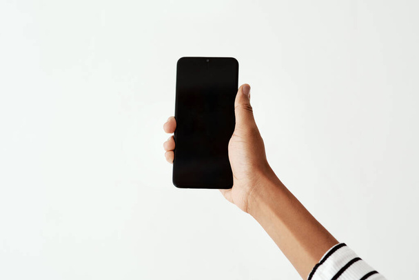 Have you seen the latest on social media. Cropped shot of a woman using a smartphone against a white studio background. - Foto, imagen