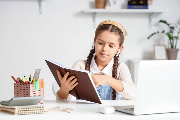 Κοριτσάκι σε ακουστικά που σπουδάζει Λογοτεχνία με online παιδαγωγό στο σπίτι - Φωτογραφία, εικόνα