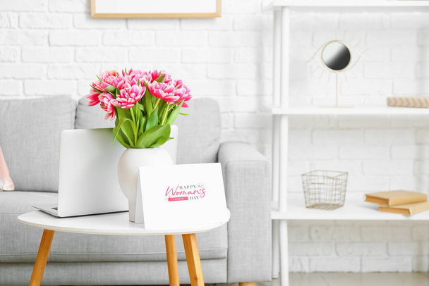 Nowoczesny laptop i wazon z bukietem tulipanów i kartką okolicznościową z tekstem DZIEŃ HAPPY WOMAN na stole - Zdjęcie, obraz