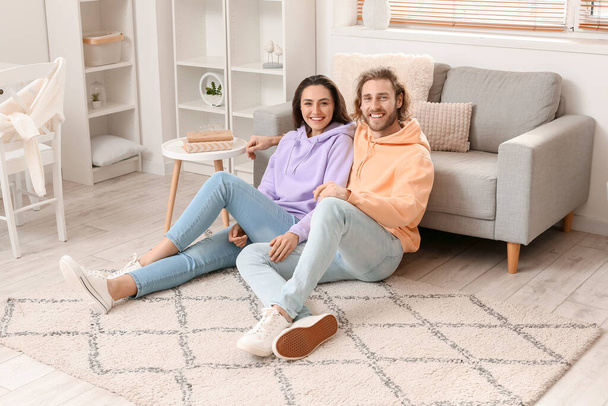 Jeune couple assis sur un tapis doux à la maison - Photo, image