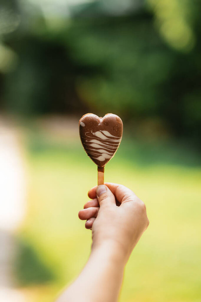 hand holding a heart shaped lollipop in the hands of a woman's day - Foto, Imagem