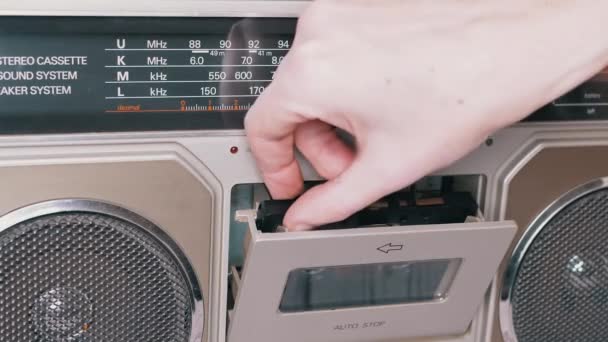 Żeńskie ręce wyjmij, odwróć starą kasetę audio z magnetofonu - Materiał filmowy, wideo