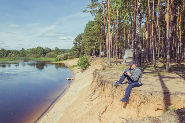 Photographer relaxes in nature near the river. Beautiful landscape outdoor recreation. - Foto, afbeelding