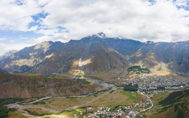 Luchtfoto van de stad Stepantsminda in het Kazbegi gebergte. Panorama van de stad in de bergen in Georgië. Bewoning in de hooglanden van de Kaukasus - Foto, afbeelding