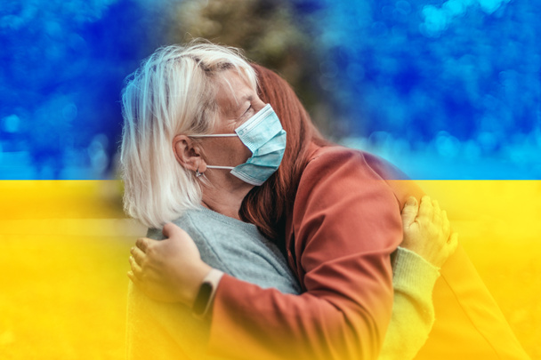 Támogatom Ukrajnát. Nincs háború. Két nő ölelkezik a parkban. Anya és lánya védő sebészeti maszkkal. Népességvándorlás - Fotó, kép