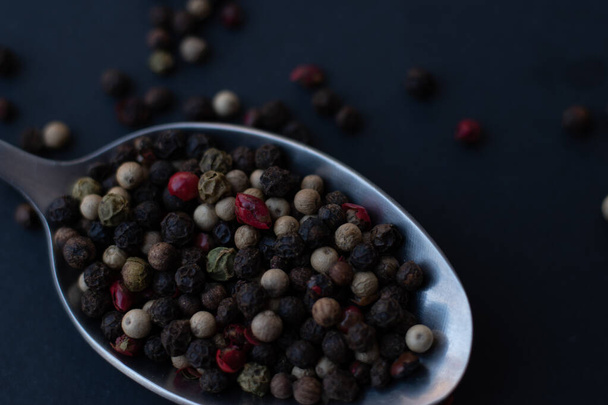 black and white peppercorns in a bowl on a dark background - Foto, afbeelding