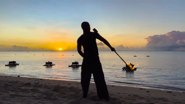 Артист крутого файер-шоу дышит огнем в темном воздухе, исполняя удивительные трюки на фоне океана - Кадры, видео