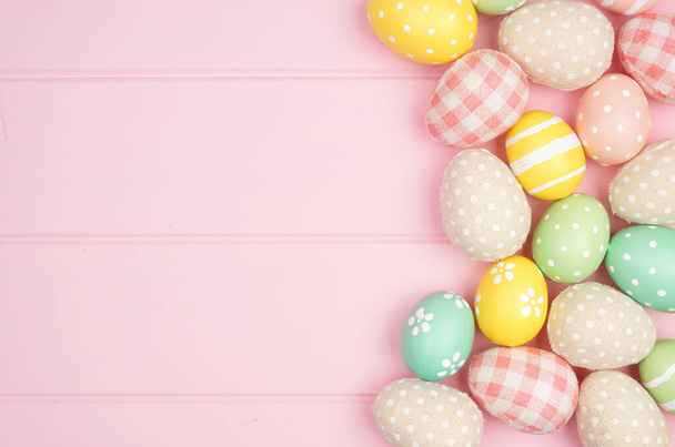 Borde lateral de Pascua con tela rústica y huevos de color pastel sobre un fondo de madera rosa. Vista de arriba hacia abajo con espacio de copia. - Foto, imagen