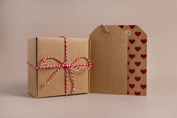 Closeup of parcels in brown wrapping paper and blank tags or labels copy space for text, isolated on beige background - 写真・画像
